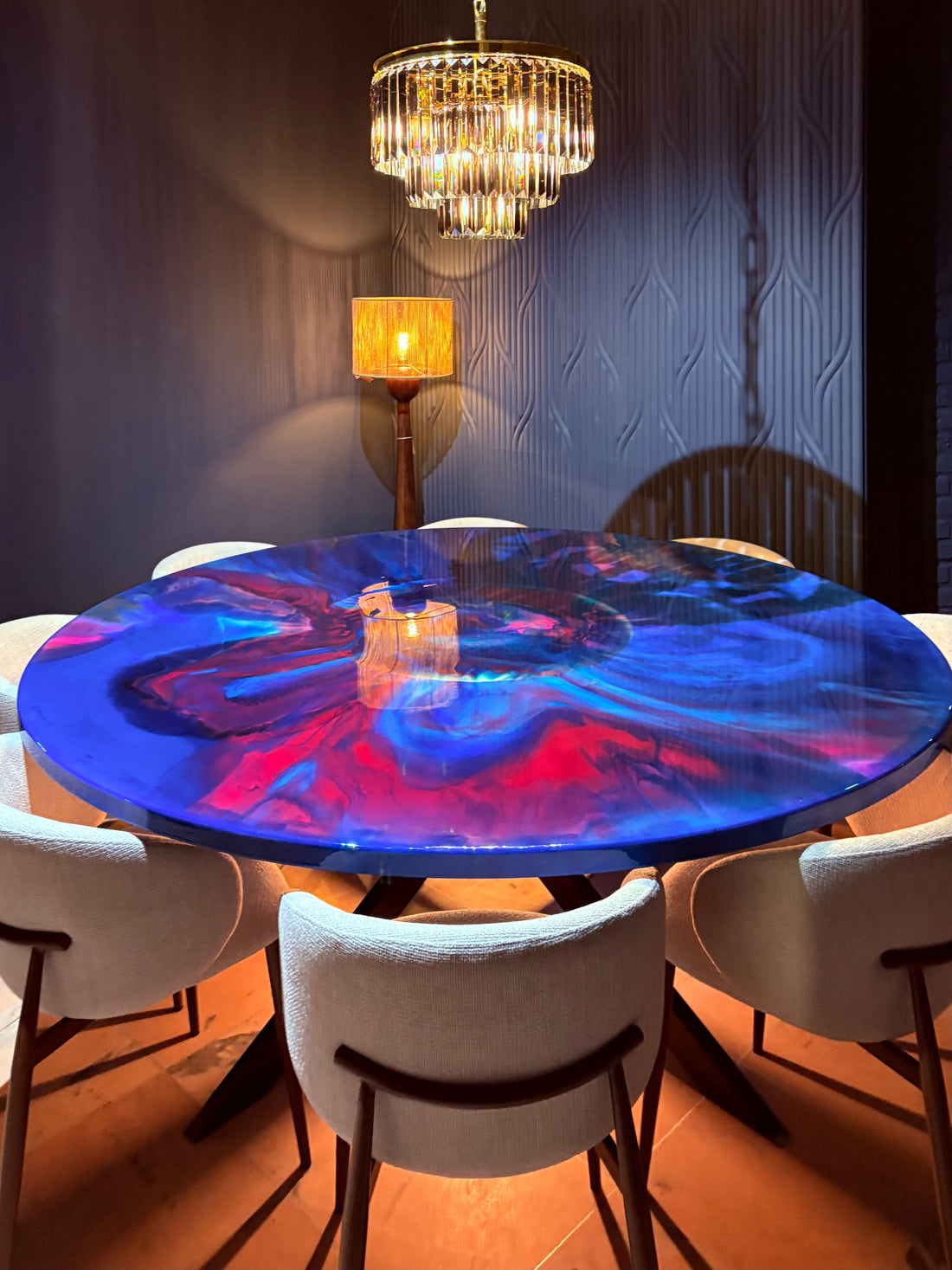 A round Illuminated Epoxy Resin Art Table, featuring swirls of electric blue and coral red, with LED lighting integrated