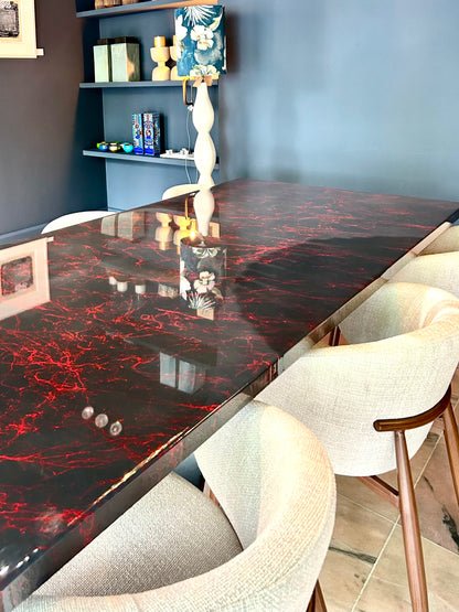 Rechthoekige donker grijze eettafel met rode marmerpatronen, omringd door beige stoelen.