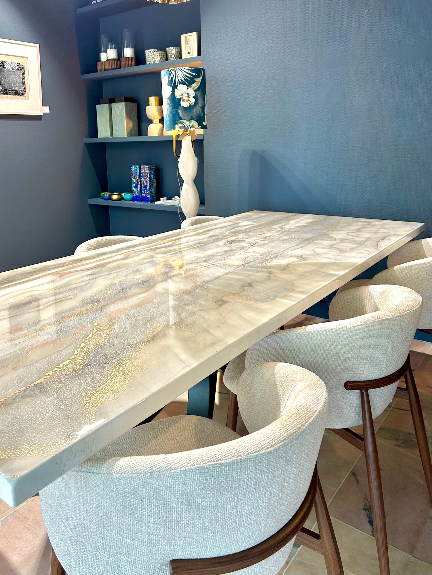Rechthoekige eettafel met brons, zilver en goud marmerlook, omringd door beige stoelen.