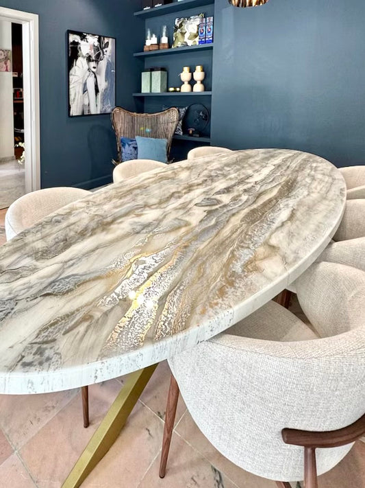 Ovale eettafel met beige-gouden en zilver marmerlook blad, omringd door lichtbeige stoelen.