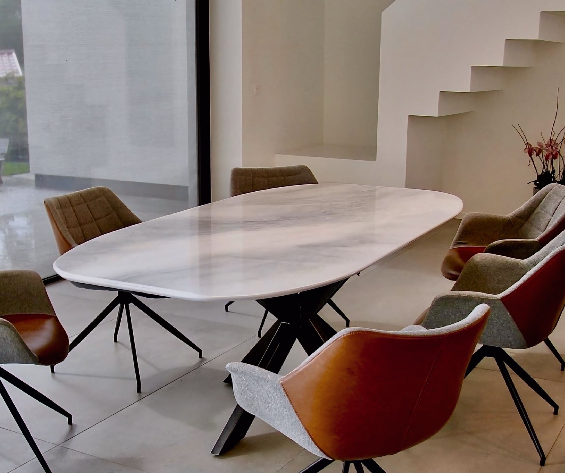 Ovale marmerlook eettafel met zes moderne armstoelen, vooraanzicht 