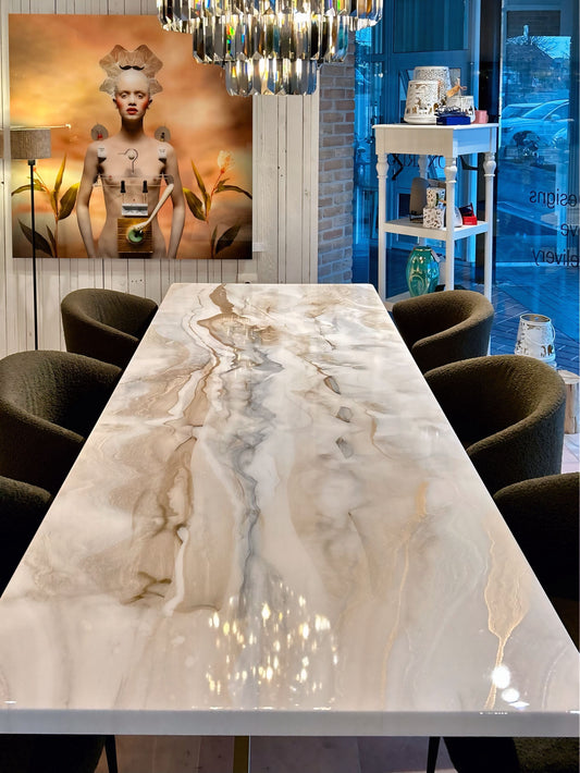 Rechthoekige eettafel met witte, zilver en goud marmerlook, omringd door beige stoelen.