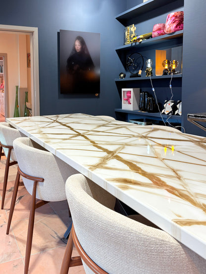 Rechthoekige witte eettafel met goudkleurige aders, omringd door beige stoelen