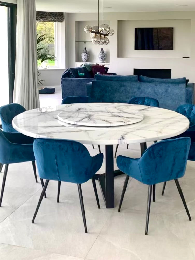 Ronde faux marmeren eettafel met draaischijf en blauwe velvet stoelen.