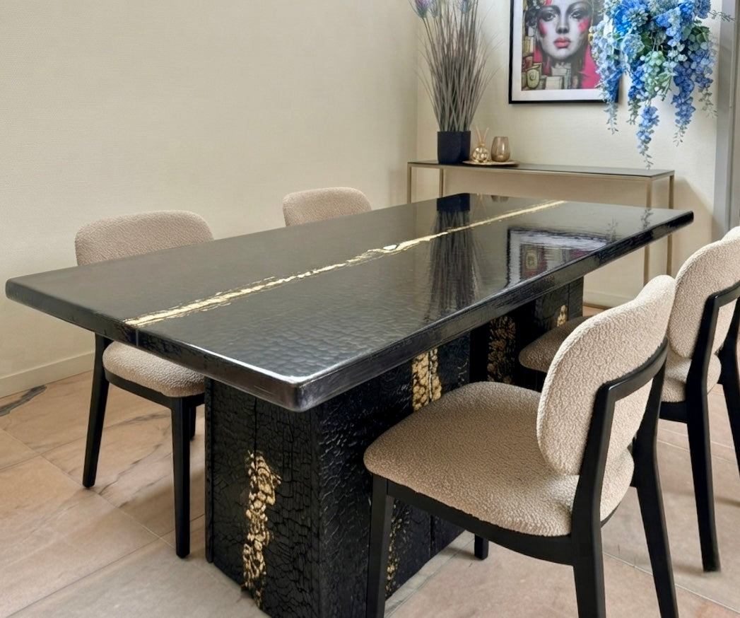 Eettafel van verbrand hout en epoxyhars met goudinleg