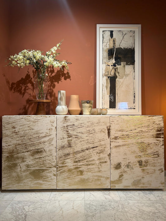 Moderne dressoir met abstract goudpatroon en decoratieve vazen.